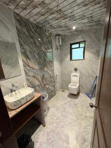 a stone bathroom with a sink and a toilet at Seven Seas Beach Resort in Diveagar