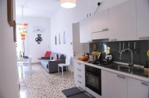 a kitchen with white cabinets and a living room at Chic Apartment Le Monde in Castellammare del Golfo