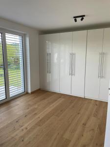 an empty room with white cabinets and a wooden floor at Schoberblick in Thalgau