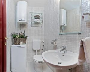 a white bathroom with a toilet and a sink at Apartman Roza in Rogoznica +55 photos