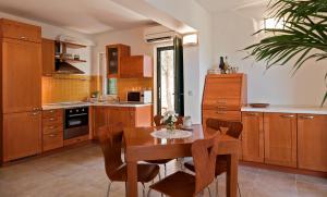 a kitchen with wooden cabinets and a wooden table with chairs at Apartman Roza in Rogoznica