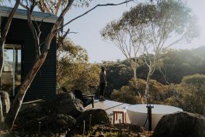 a man standing on a deck next to a bath tub at Moonbah Escapez in Moonbah