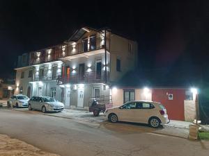 two cars parked in front of a building at night at Apartman Radoman in Cetinje