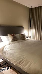 a bed with white sheets and pillows in a bedroom at شقة هادئة مودرن in Al Khobar