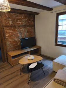 a living room with a table and a television at Logis Saint Martin in Colmar