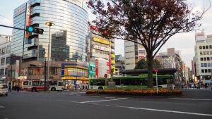 a busy city street with a green bus at 神谷戸建 in Tokyo