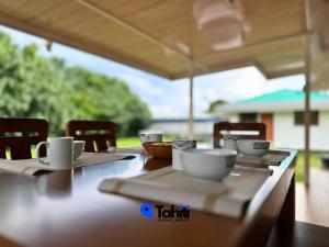 a wooden table with cups and saucers on it at Moorea Here Lodge house in Atiha