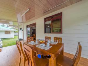 a dining room with a wooden table and chairs at Moorea Here Lodge house in Atiha