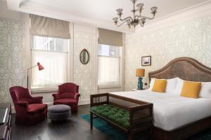 a bedroom with a bed and two chairs and a chandelier at The Beekman, A Thompson Hotel, by Hyatt in New York