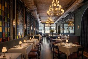 a restaurant with white tables and chairs and chandeliers at The Beekman, A Thompson Hotel, by Hyatt in New York
