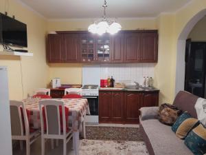 a kitchen with wooden cabinets and a table and a couch at Apartman Radoman in Cetinje