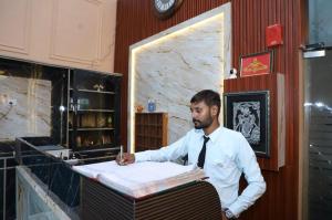 a man in a tie writing on a piece of paper at Hotel Black Stone Palace in Ghaziabad
