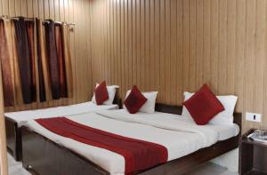 two beds with red and white pillows in a room at hotel sooryoday j in Varanasi