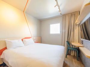 a hotel room with a bed and a window at Ibis Budget La Rochelle Puilboreau in Puilboreau
