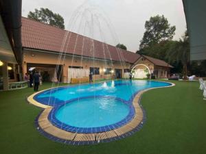 a large blue swimming pool in front of a building at Banna Resort in Ban Khlong Kadon (1)