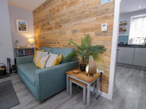a living room with a blue couch and a wooden wall at Y Bwthyn in Llanbedr