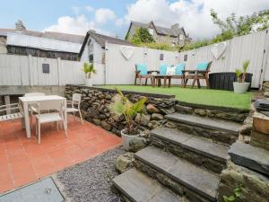 a backyard with a stone wall and a table and chairs at Y Bwthyn in Llanbedr