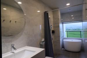 a bathroom with a sink and a tub and a mirror at Go Chishang B&B in Chishang +41 photos