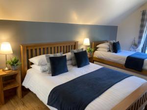 a bedroom with two beds with blue and white pillows at Redroofs Barn - 28184 in Weston +6 photos