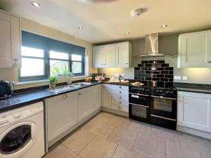 a kitchen with white cabinets and a washer and sink at Redroofs Barn - 28184 in Weston