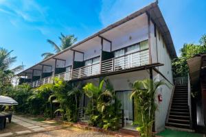 a building with balconies and palm trees at YogiTree Beach Resort & Cafe - 100m from Morjim Beach in Morjim