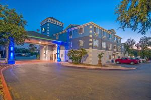 a building with a car parked in front of it at Days Inn & Suites by Wyndham San Antonio North/Stone Oak in San Antonio
