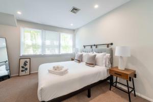 a bedroom with a large white bed with a night stand at Hampton Bays Townhouse - Pool Beach Access in Hampton Bays