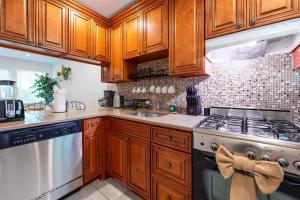 a kitchen with wooden cabinets and a stove top oven at Hampton Bays Townhouse - Pool Beach Access in Hampton Bays