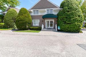 a house with large trees in front of it at Hampton Bays Townhouse - Pool Beach Access in Hampton Bays +25 photos