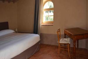 a bedroom with a bed and a desk and a window at Borgo Le Moraiole in Massa Marittima