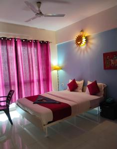 a bedroom with a large bed with pink curtains at GM Hospitality Services pune in Pune