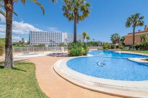 a swimming pool with palm trees and a hotel in the background at Can Tomeu in Calas de Mallorca