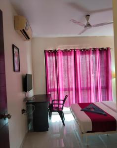 a bedroom with a bed and a desk and a window at GM Hospitality Services pune in Pune