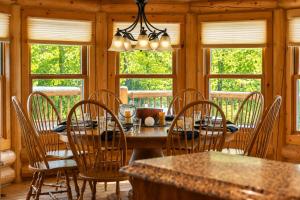a dining room with a table and chairs and windows at Fiddler Lake Resort - Deer 79 in Mille-Isles