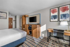 a hotel room with a bed and a desk and a tv at AmericInn by Wyndham Delafield-Milwaukee in Delafield