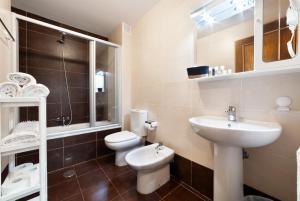 a white bathroom with a sink and a toilet at Apartamentos El Escudo Centro in Ribadesella