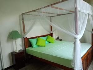a bedroom with a canopy bed with green pillows at Mariya Villa in Unawatuna