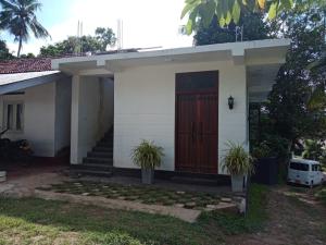 a small white house with a red door at Mariya Villa in Unawatuna
