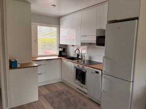 a kitchen with white cabinets and a refrigerator at Koivukuja in Köyliö