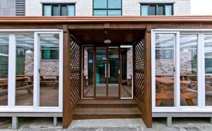 a building with a wooden porch with glass doors at Daecheon sinhwa pension in Boryeong