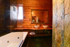 a bathroom with two sinks and a tub and a mirror at Aldea Naukana Posada Boutique in Pucón