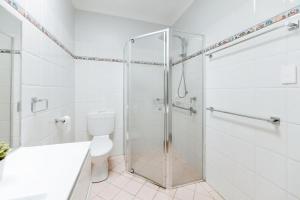 a white bathroom with a shower and a toilet at Iconic Escape Nowra in Nowra +9 photos