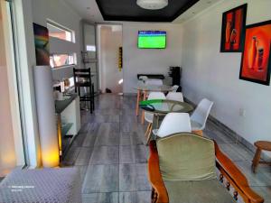 a room with tables and chairs and a tv on the wall at Dante Guest house in Alberton