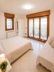 a bedroom with two beds and two windows at Residence Roberta con piscina - Agenzia Cocal in Caorle