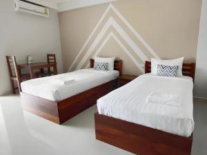 a bedroom with two beds and a table with a desk at Iyara Residence in Trat