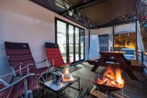 a screened in porch with a fireplace and chairs at Jade Byeolbit Caravan in Chuncheon