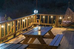a wooden picnic table on a deck at night at Jade Byeolbit Caravan in Chuncheon