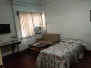 a bedroom with a bed and a chair and a television at The Boulevard Hotel in Jamshedpur