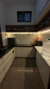 a kitchen with white cabinets and a counter top at Yashaswi Hilldeck in Sondekoppa +18 photos