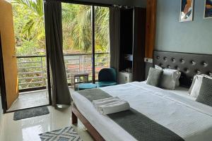 a bedroom with a bed and a large window at YogiTree Beach Resort & Cafe - 100m from Morjim Beach in Morjim